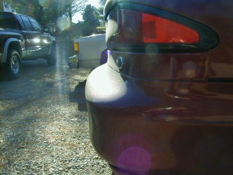 1994 Ford Probe - Close-up of a car's rear, showing the taillight and quarter panel. Other vehicles are visible in the background.