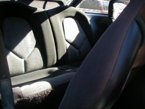 1994 Ford Probe - Interior view of the rear seats of a car, with a glimpse of another vehicle outside.