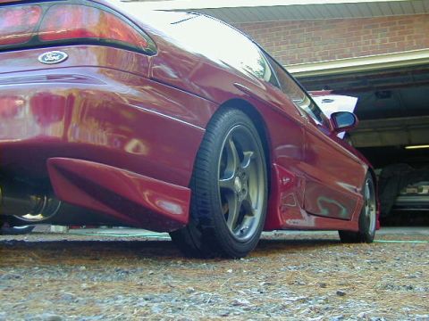 1994 Ford Probe - Rear quarter panel view of a red 1994 Ford Probe with custom body kit parked in a garage.