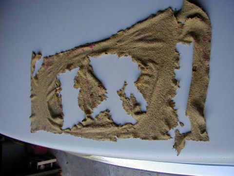 1994 Ford Probe - Torn tan fabric with cutouts is placed on a white surface, showing red specks.