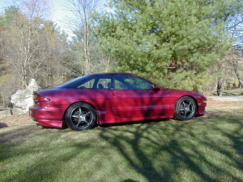 1994 Ford Probe - Side view of a red 1994 Ford Probe coupe parked outdoors on a sunny day.