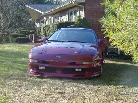 1994 Ford Probe - Front view of a red 1994 Ford Probe parked on a lawn near a residential building.