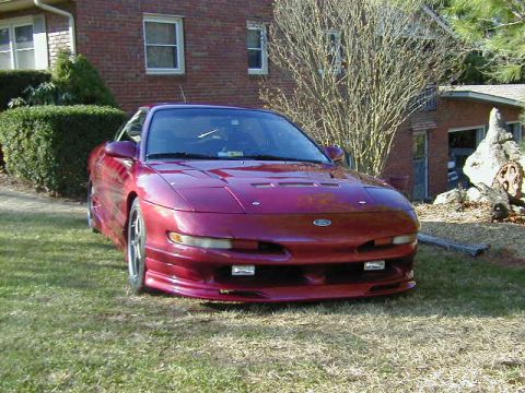 1994 Ford Probe - A red 1994 Ford Probe is shown in a three-quarter front view, parked on a lawn with a house in the background.