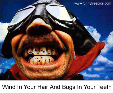 1989 Ford Bronco - A man with goggles and a red scarf has bugs in his teeth, with the sky and clouds in the background.