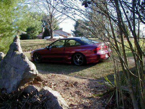 1994 Ford Probe - A red coupe sits on a grassy lawn, partially obscured by tree branches.
