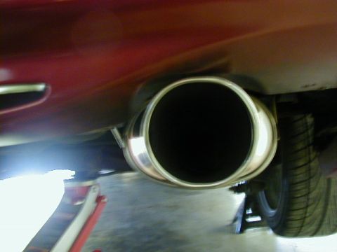 1994 Ford Probe - Close-up of a car's exhaust pipe, with a tire and part of a jack visible in the background.
