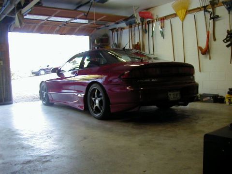 1994 Ford Probe - A maroon 1994 Ford Probe is parked inside a garage, with gardening tools hanging on the wall.