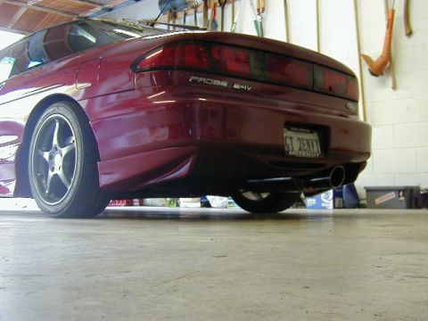 1994 Ford Probe - The rear of a red 1994 Ford Probe is visible, custom wheels and dual exhaust pipes.
