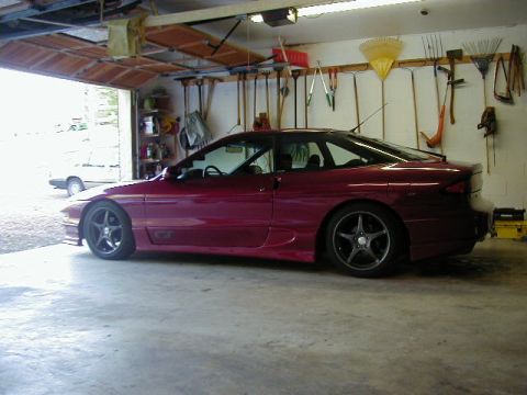 1994 Ford Probe - A maroon 1994 Ford Probe GT is parked in a garage with tools on the wall and another vehicle visible outside.