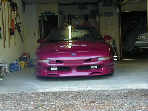 1994 Ford Probe - A maroon Ford Probe is parked in a garage with tools on the wall and another vehicle covered in the background.