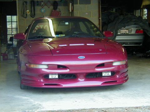 1994 Ford Probe - A maroon Ford Probe is parked in a garage, showing its front end and headlights.