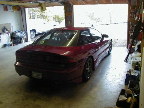 1994 Ford Probe - A red 1994 Ford Probe is parked inside a garage, showing its rear profile.