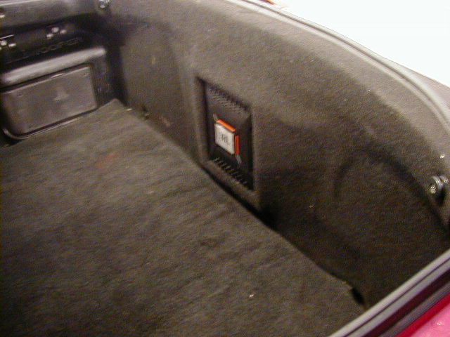 Car trunk interior with dark carpet and a JBL speaker mounted on the side panel