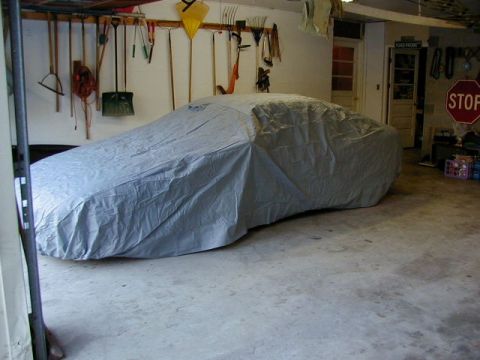 1994 Ford Probe - A car is covered by a tarp in a garage, with various tools hanging on the wall behind it.