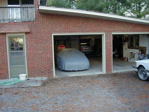 1994 Ford Probe - A car is covered in a garage, with another vehicle visible outside.