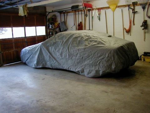 1994 Ford Probe - A car is covered by a gray car cover and parked in a garage with tools on the wall.
