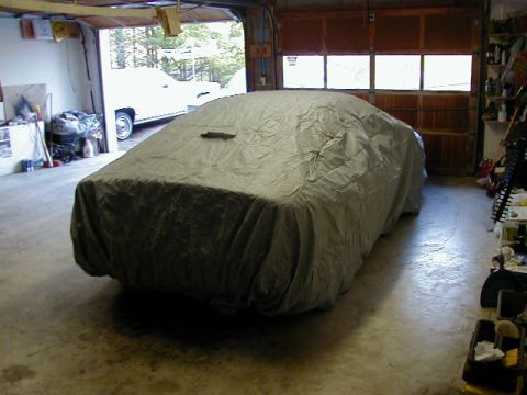 1994 Ford Probe - A car is covered with a tarp in a garage, with another vehicle visible in the background outside background outside background outside back…