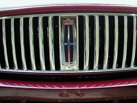 1994 Ford Probe - Close-up of a red car's front grille chrome vertical bars and the Lincoln emblem. Text at the bottom reads 'SUPERMOTORS.NET'.
