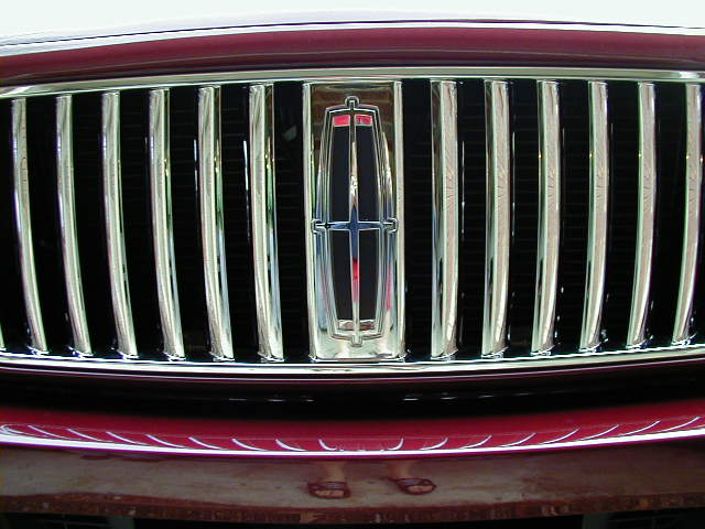 Red car grille with chrome vertical bars and Lincoln emblem