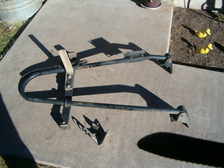Black spare tire rack with strap, lying on concrete