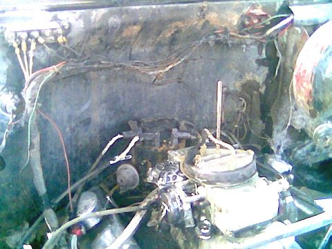 1976 GMC C/K Pickup - The engine bay of a 1976 GMC C/K Pickup is visible, with a focus on the carburetor and associated wiring.