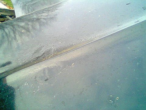 1976 GMC C/K Pickup - Close-up view of a truck hood showing signs of wear and tear, including rust along the seam.
