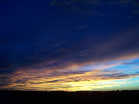 1994 Ford Probe - Dramatic sunset sky with wispy clouds painted in hues of yellow, orange, and blue.