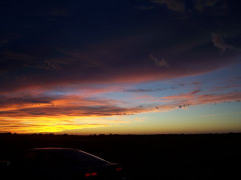 1994 Ford Probe - A car is silhouetted against a vibrant sunset sky with dramatic clouds.
