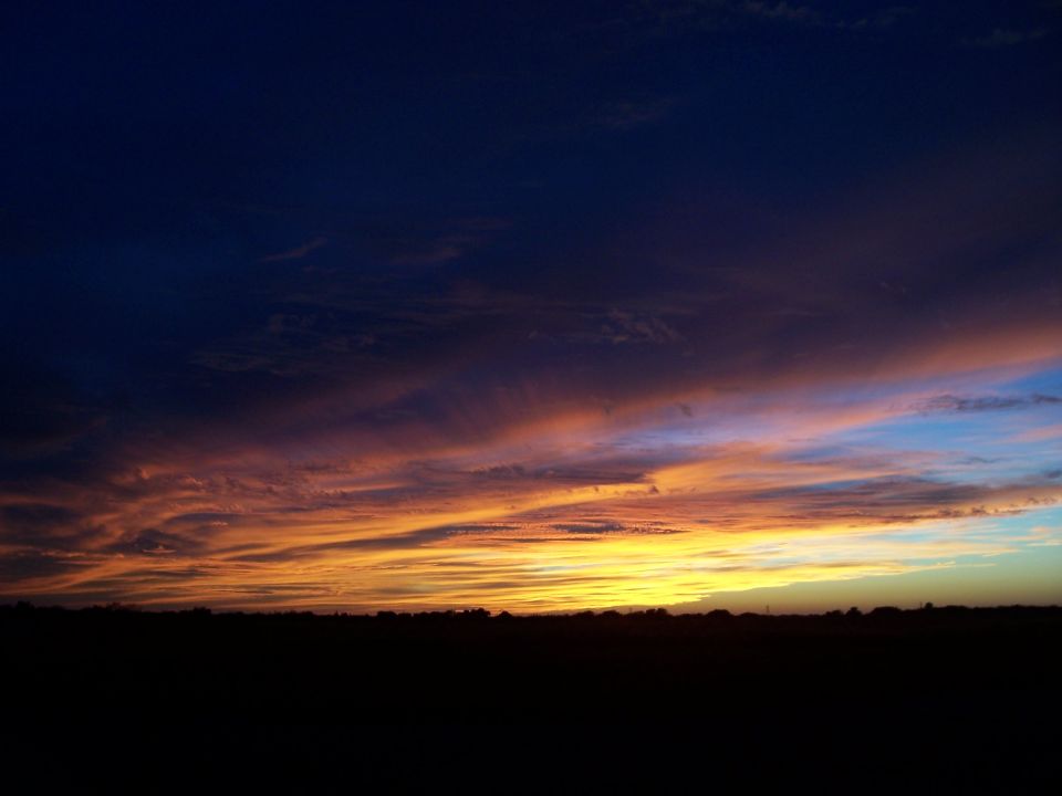 Sunset sky with orange and blue clouds over a dark horizon. "SUPERMOTORS" logo visible