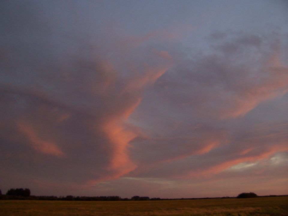 Sunset clouds over a field with a distant treeline. Supermotors.net watermark visible