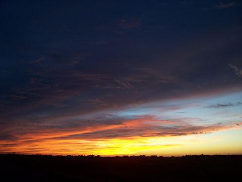 1994 Ford Probe - The sky displays a vibrant sunset with dramatic cloud formations and a bright horizon.