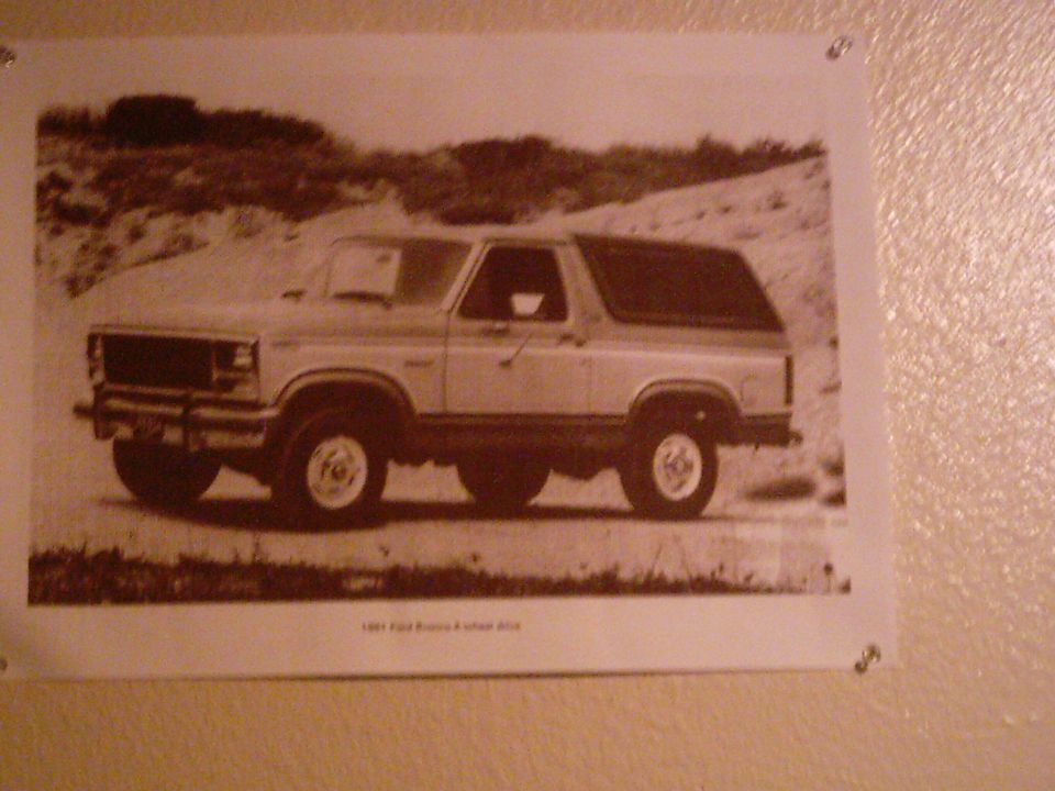 1986 Ford Bronco parked on a dirt road with sand dunes in the background