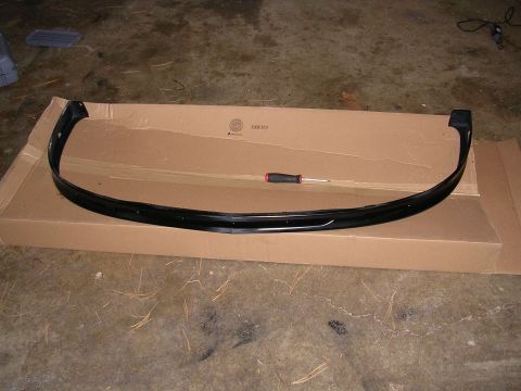 1996 Ford Probe - A black car bumper lip is placed on a cardboard box, with a screwdriver nearby.