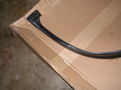 1996 Ford Probe - A detached car trim piece lies on a cardboard surface, showing its curved shape and mounting bracket.