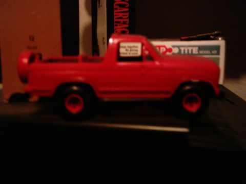 1986 Ford Bronco - A red toy truck is shown from the side, with a spare tire mounted on the rear.