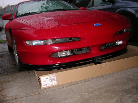 1996 Ford Probe - A red 1996 Ford Probe is parked on a cardboard box, showing its front end with a black lip kit.