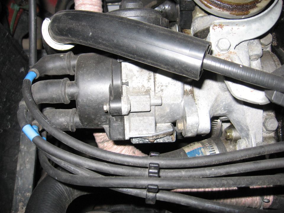 Close-up of an engine distributor cap with spark plug wires and boots in engine bay