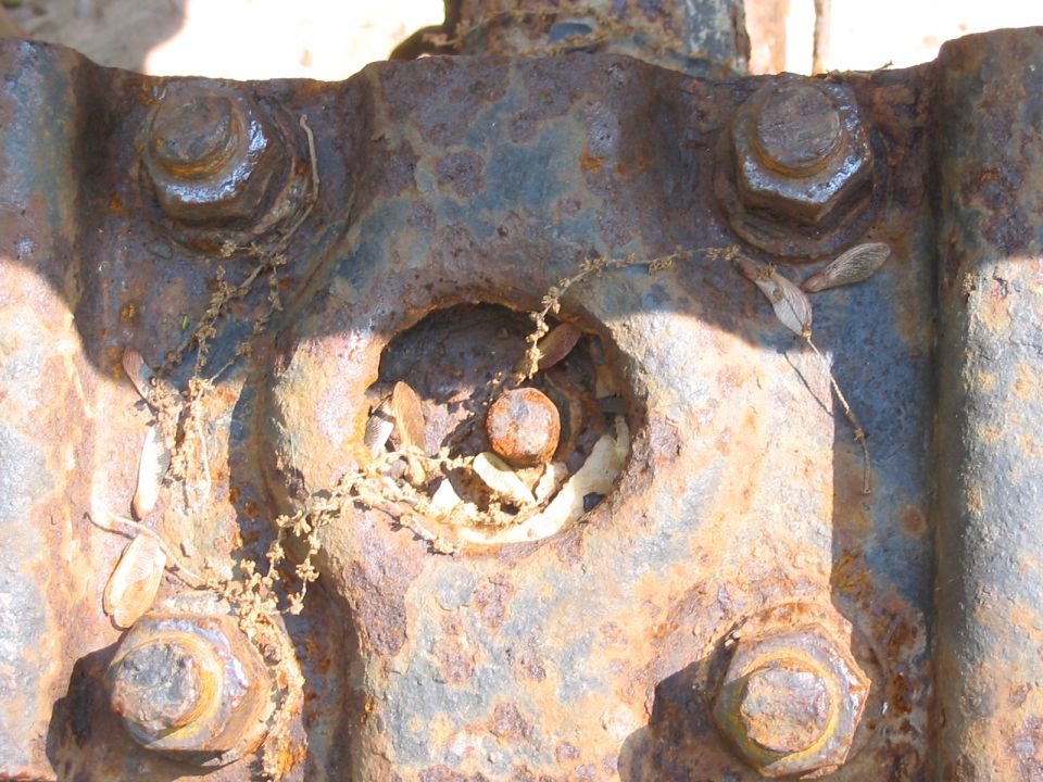Close-up of rusted metal part with large bolts and debris