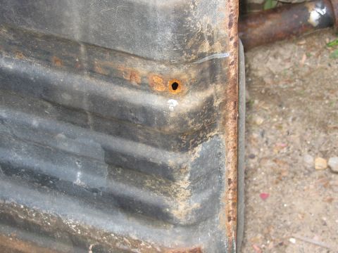 1985 Ford F-350 - A close-up of a rusty, corrugated metal part, possibly a fuel tank, with visible texture and damage.