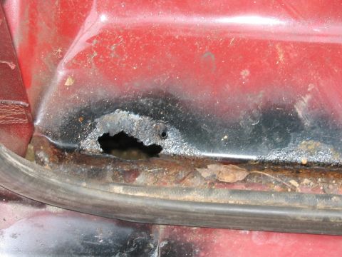 1985 Ford F-350 - Significant rust damage is visible on the lower body panel of this red vehicle.