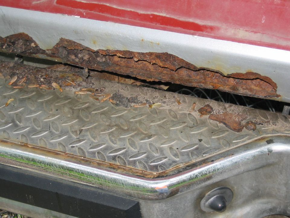 Close-up of heavily rusted metal trim and diamond plate on a vehicle's lower body
