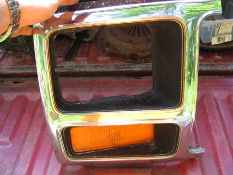 1985 Ford F-350 - A chrome headlight bezel with an amber turn signal is held up, revealing a clutch assembly in the background.