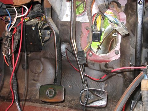 1985 Ford F-350 - Close-up of the floorboard and pedals, revealing complex wiring and a fuse box.