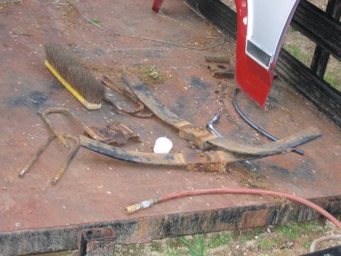 1985 Ford F-350 - Vehicle parts, including a fender and leaf springs, are scattered on a rusty trailer.