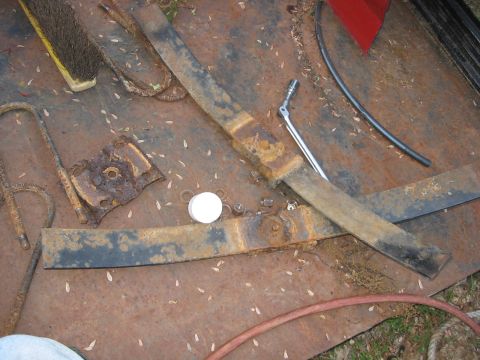 1985 Ford F-350 - Leaf springs and a socket wrench lie on a rusty surface, with a brush and hose also visible.