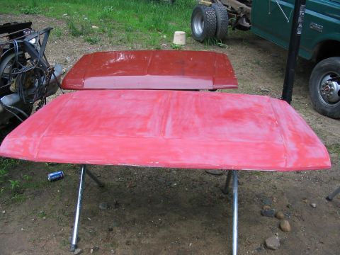 1985 Ford F-350 - Two red car hoods are prepped for work, with a green truck in the background.