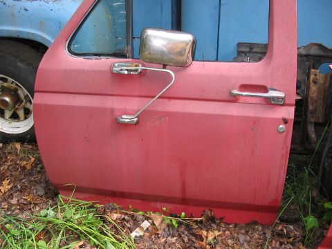 1985 Ford F-350 - A red truck door is shown from the side, with a chrome side mirror and door handle visible.