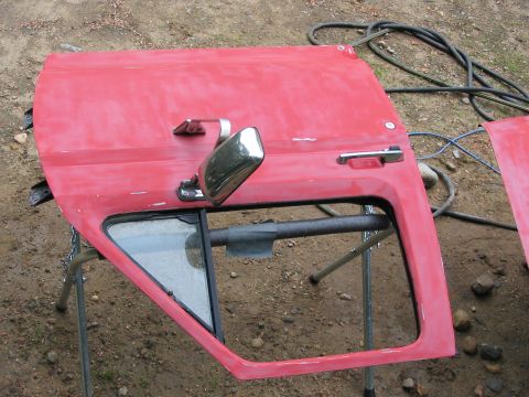 1985 Ford F-350 - A red truck door, likely for a Ford F-350, is prepped for paint on sawhorses.