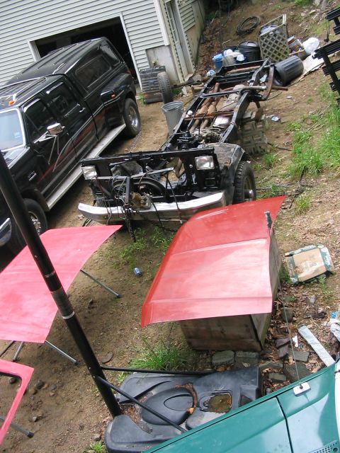 1985 Ford F-350 - A truck chassis is being worked on in a yard, with a black pickup truck parked nearby.