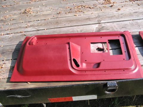 1985 Ford F-350 - Red interior door panel removed from a vehicle, showing cutouts for controls.